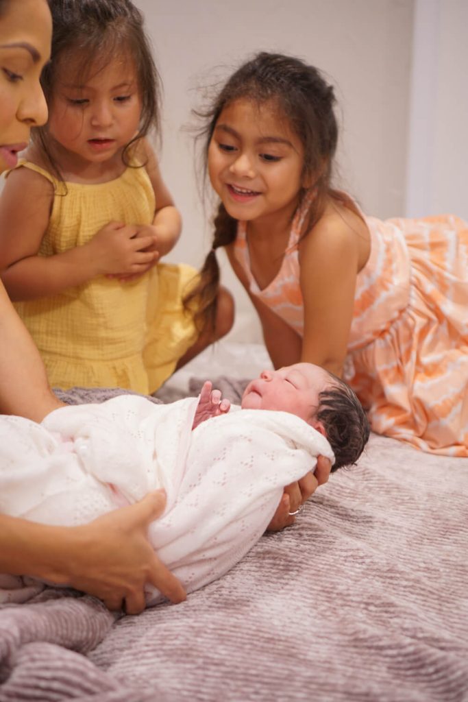 journey birth center conroe texas. out of hospital birth midwife. family centered birth. image of mother holder her newborn with her other 2 young children watching